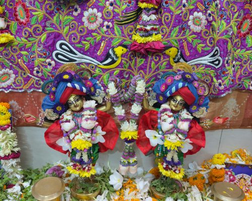 Colorful Indian religious dolls adorned with flowers in a festive setting.